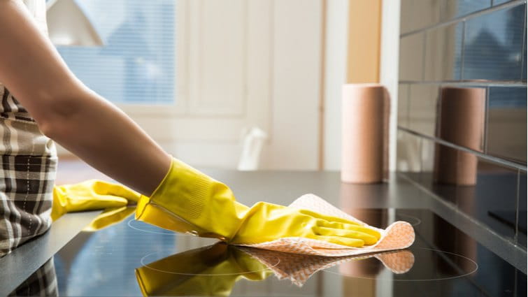 Mujer con guantes limpiando una placa de inducción