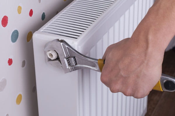 mano de hombre purgando un radiador con una llave inglesa