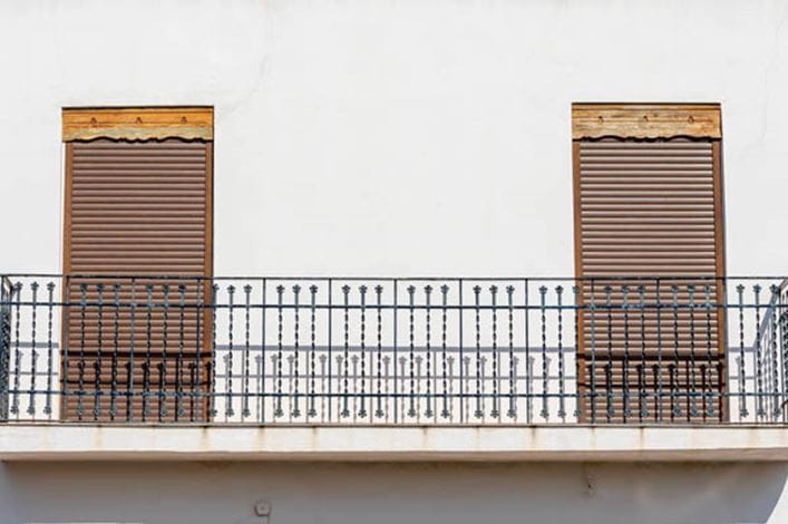 balcón de la fachada de una casa donde se han roto las persianas enrollables