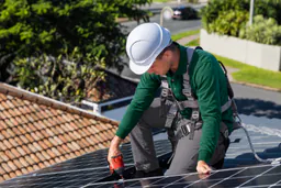 Técnico de Reparalia con casco y arnés instalando placas solares en un tejado