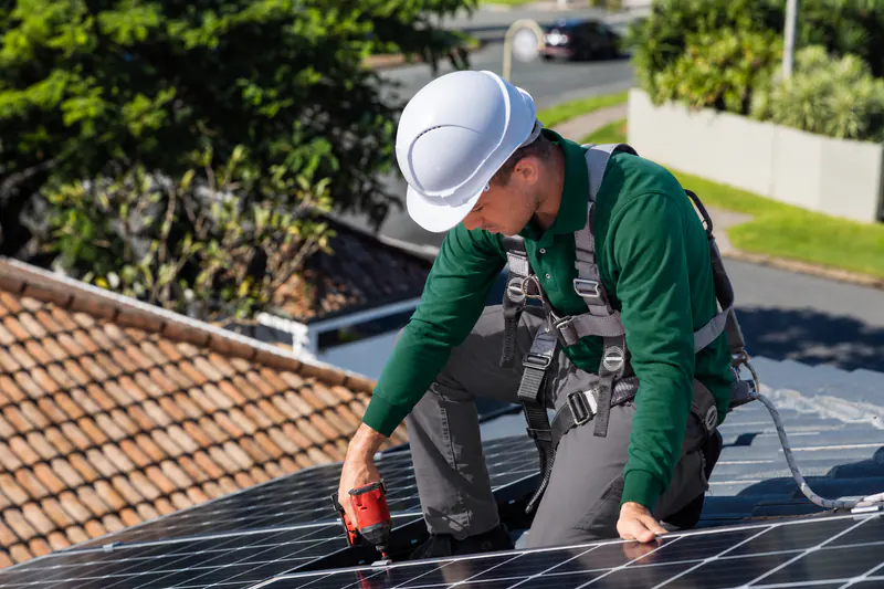 Técnico de Reparalia con casco y arnés instalando placas solares en un tejado